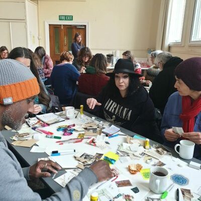 Arts & Health artists workshop. Various people sat doing crafts at tables.